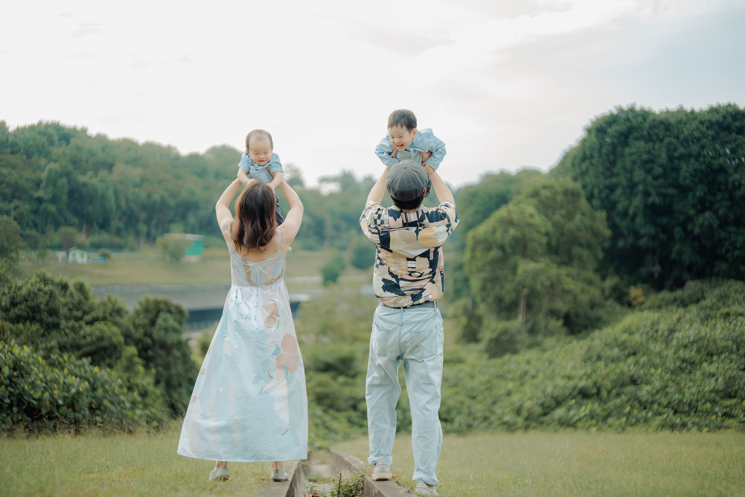 Family enjoying a playful outdoor photoshoot in casual outfits against a natural landscape.