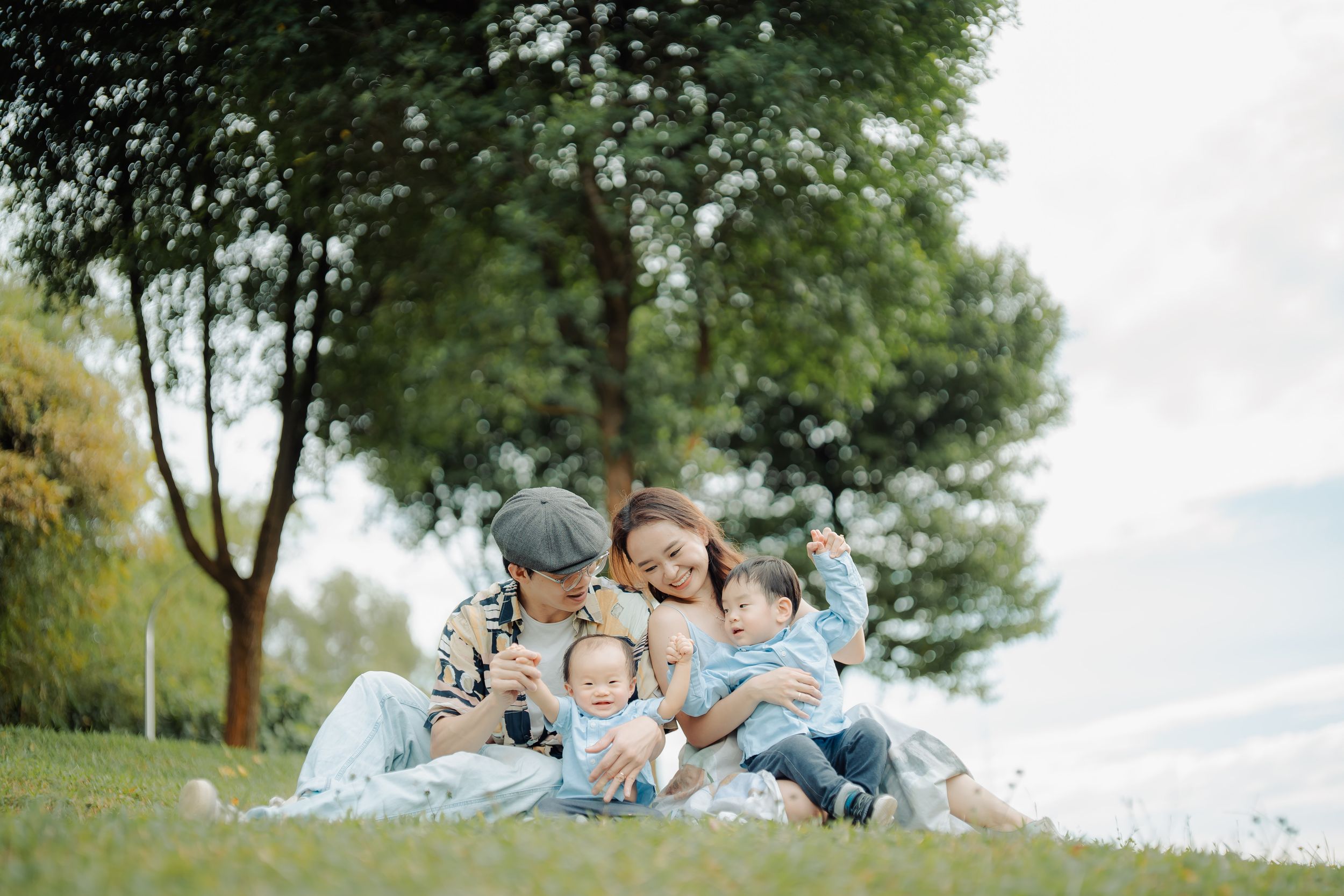 Family portrait session in a lush green park setting showing candid moments of connection.