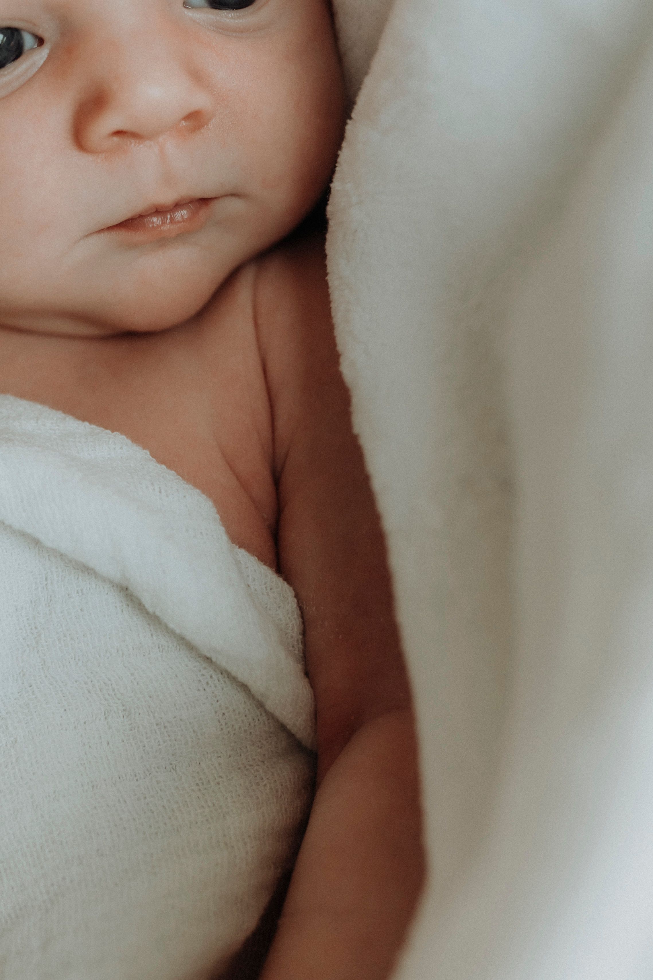 Close-up of a baby's face nestled in soft white blankets.