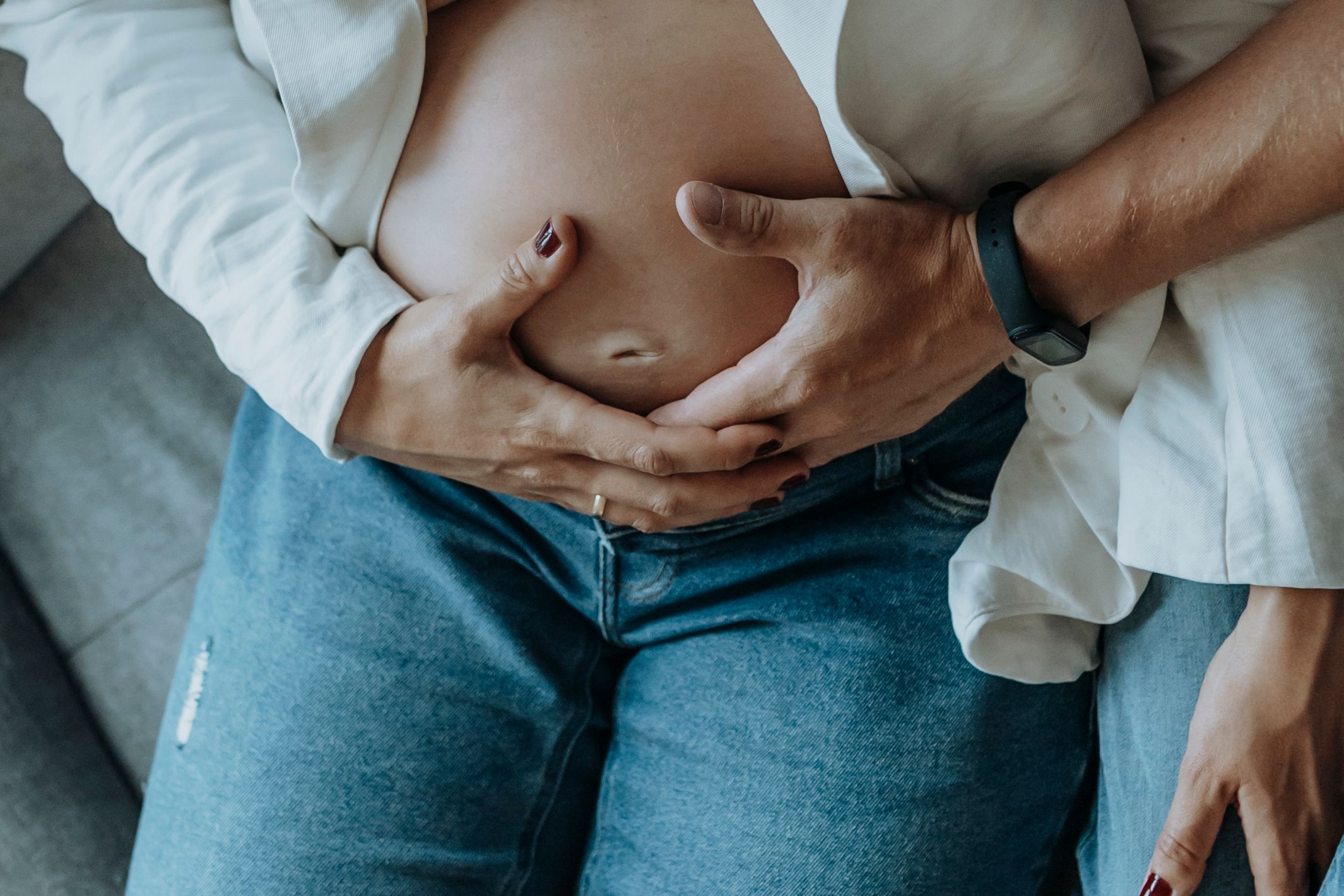 Series of intimate maternity photos showing a pregnant belly with hands gently cradling it.