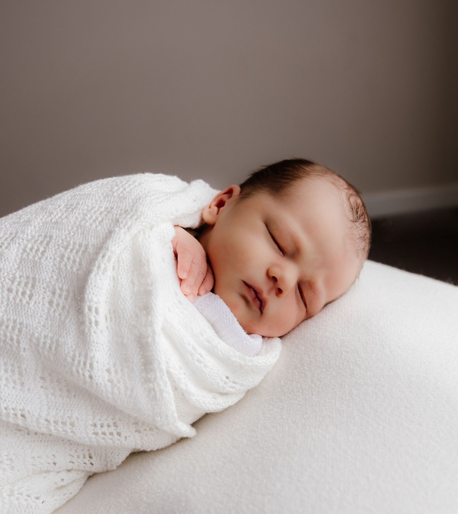 Newborn baby peacefully sleeping in a soft blanket, photographed in natural studio light in the Blue Mountains, NSW, near Sydney, Australia.