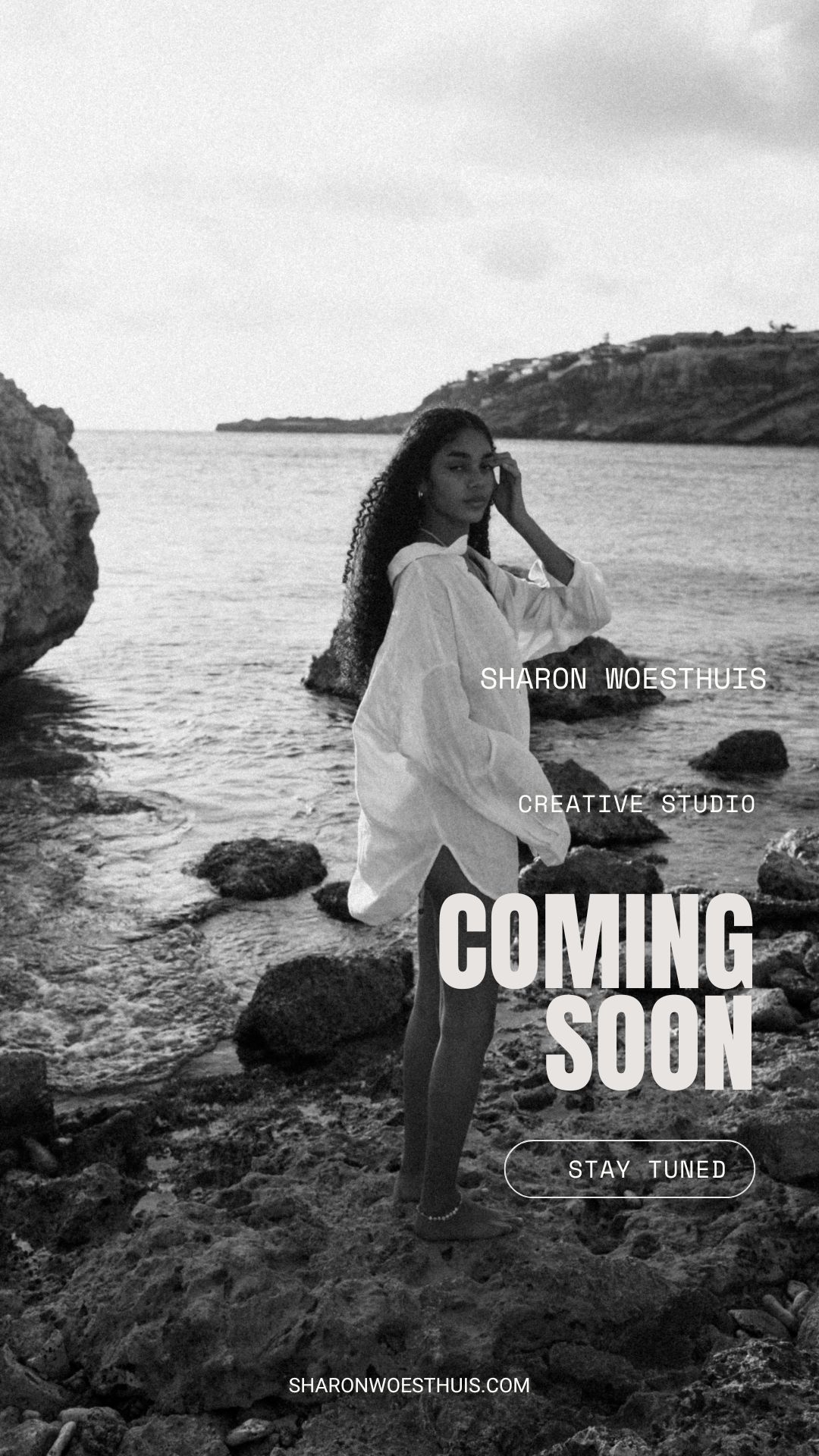 Black and white promotional image of model on rocky coastline with 'Coming Soon' text overlay.