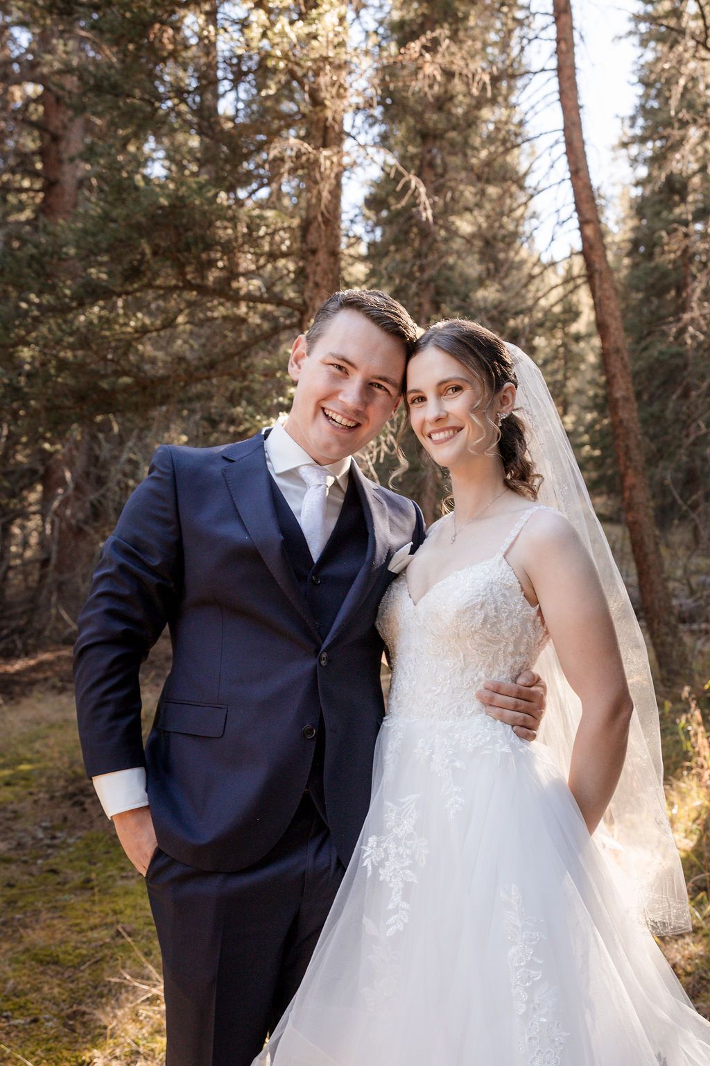 A couple shares joyful moments in a forest setting during their wedding photoshoot.