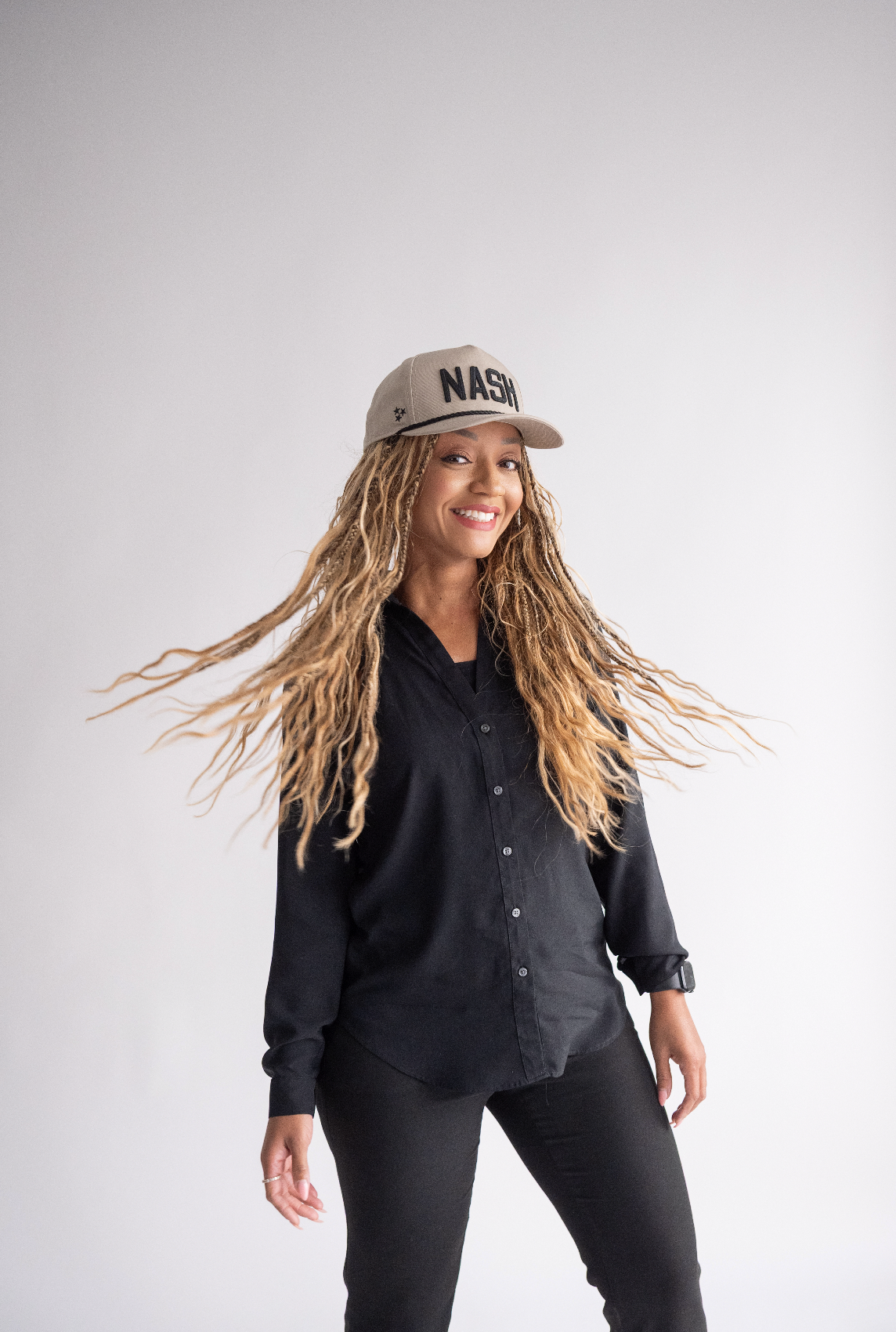 A person in a black outfit and NASA cap dances energetically against a white background.