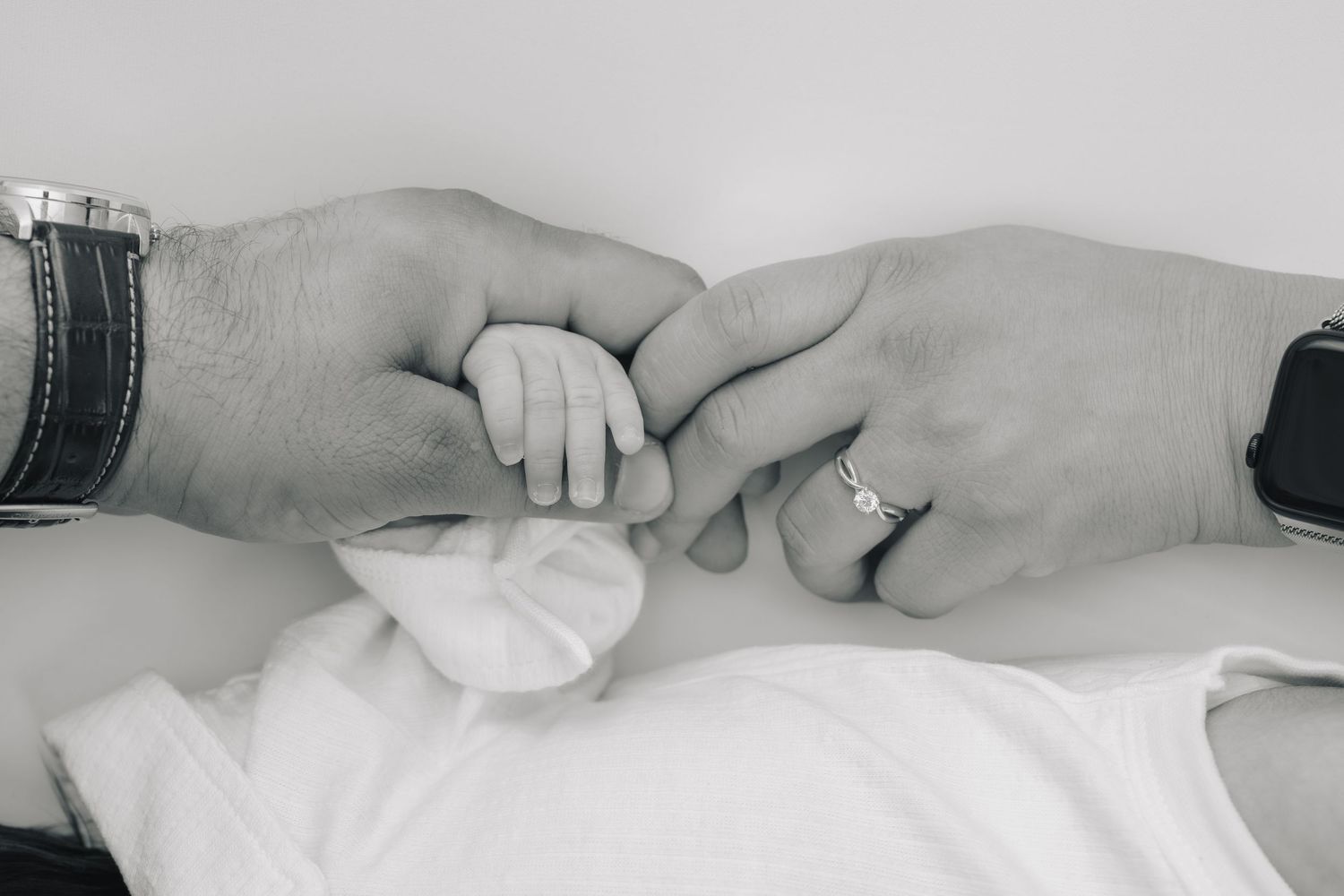 A series of black and white photographs showing hands in various gentle poses against a light background.