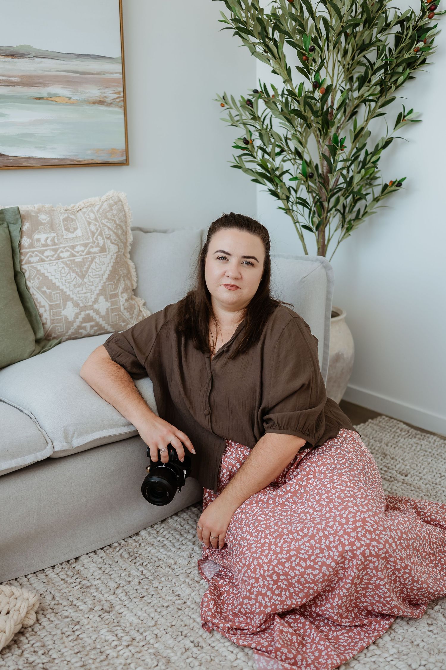 Photographer with camera relaxing on cozy floor setting with coastal decor at gladstone photography studio.
