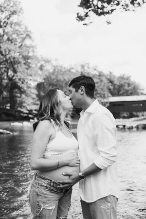 A romantic couple embraces while standing in shallow water during a black and white photoshoot.