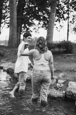 Black and white photo series of a couple playing and splashing in a creek or stream on a sunny day.