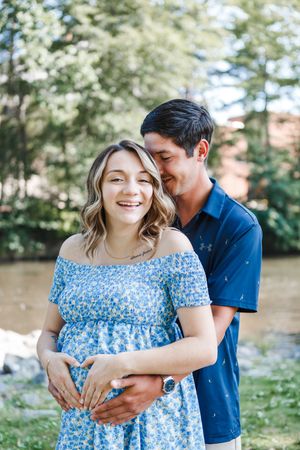 Couple embracing outdoors in a natural setting with a blue floral dress and navy shirt.