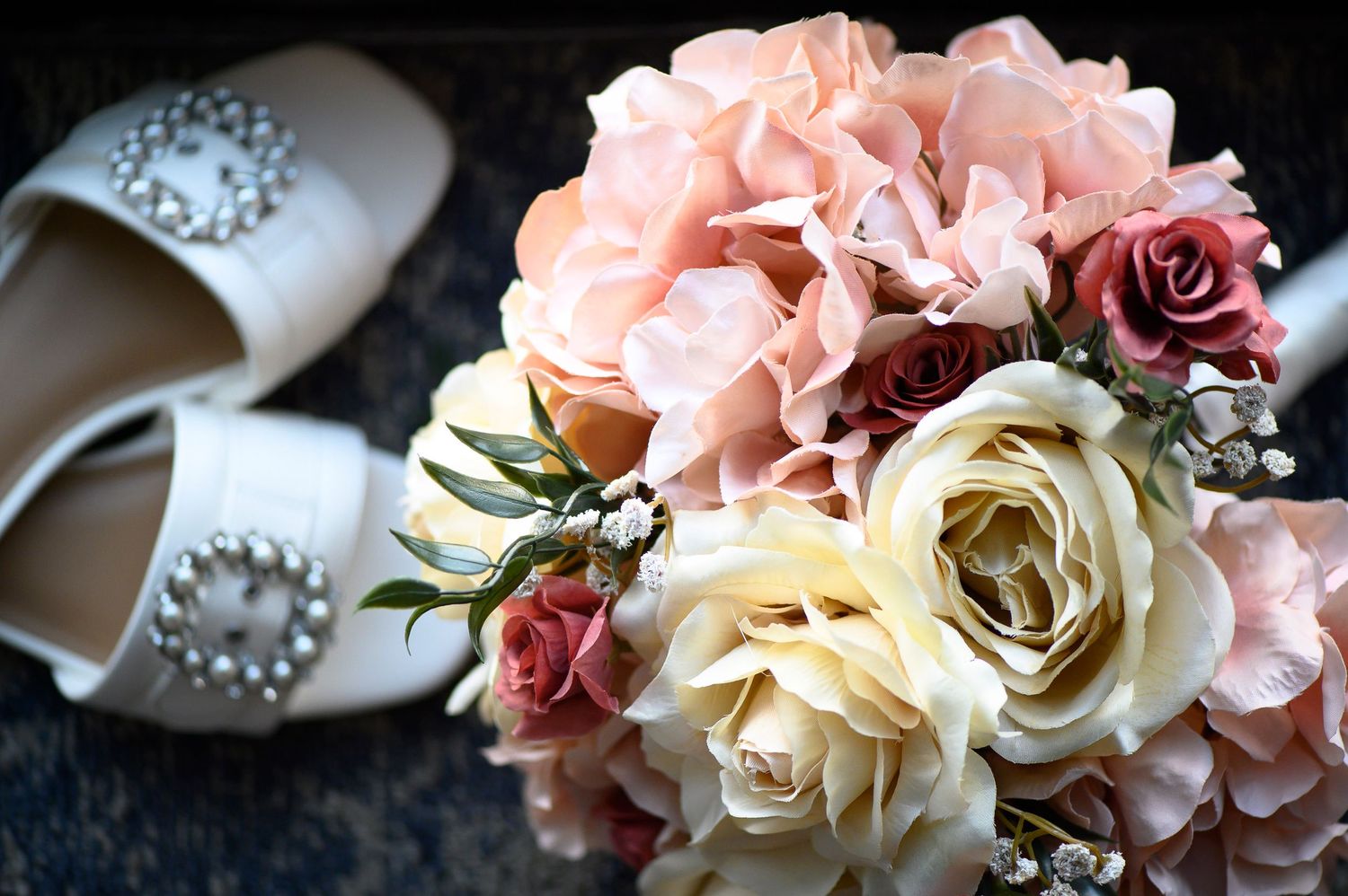 A delicate arrangement of pink and cream roses with scattered pearls creates an elegant wedding decor detail. wedding photos in alpharetta,