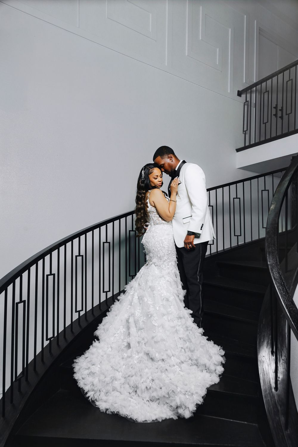 A series of romantic wedding photos showing a couple embracing on an elegant curved staircase with black railings.