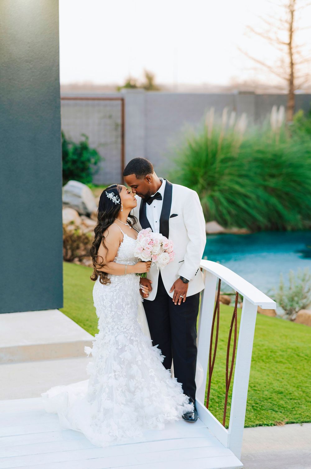 A romantic wedding photo series showing a couple in formal attire embracing on a grassy lawn at sunset.