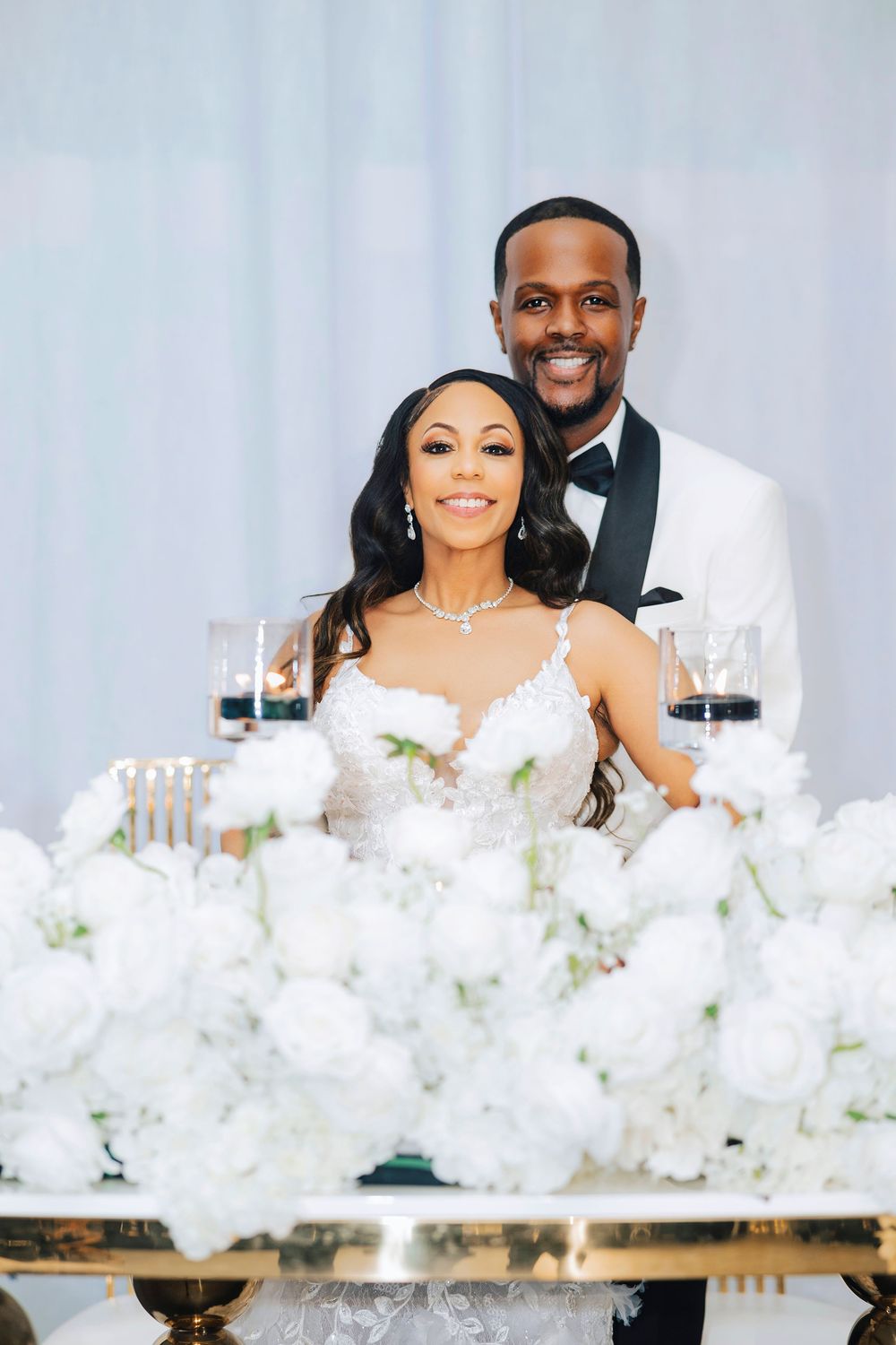 Newlyweds share intimate moments at their reception table decorated with white flowers.