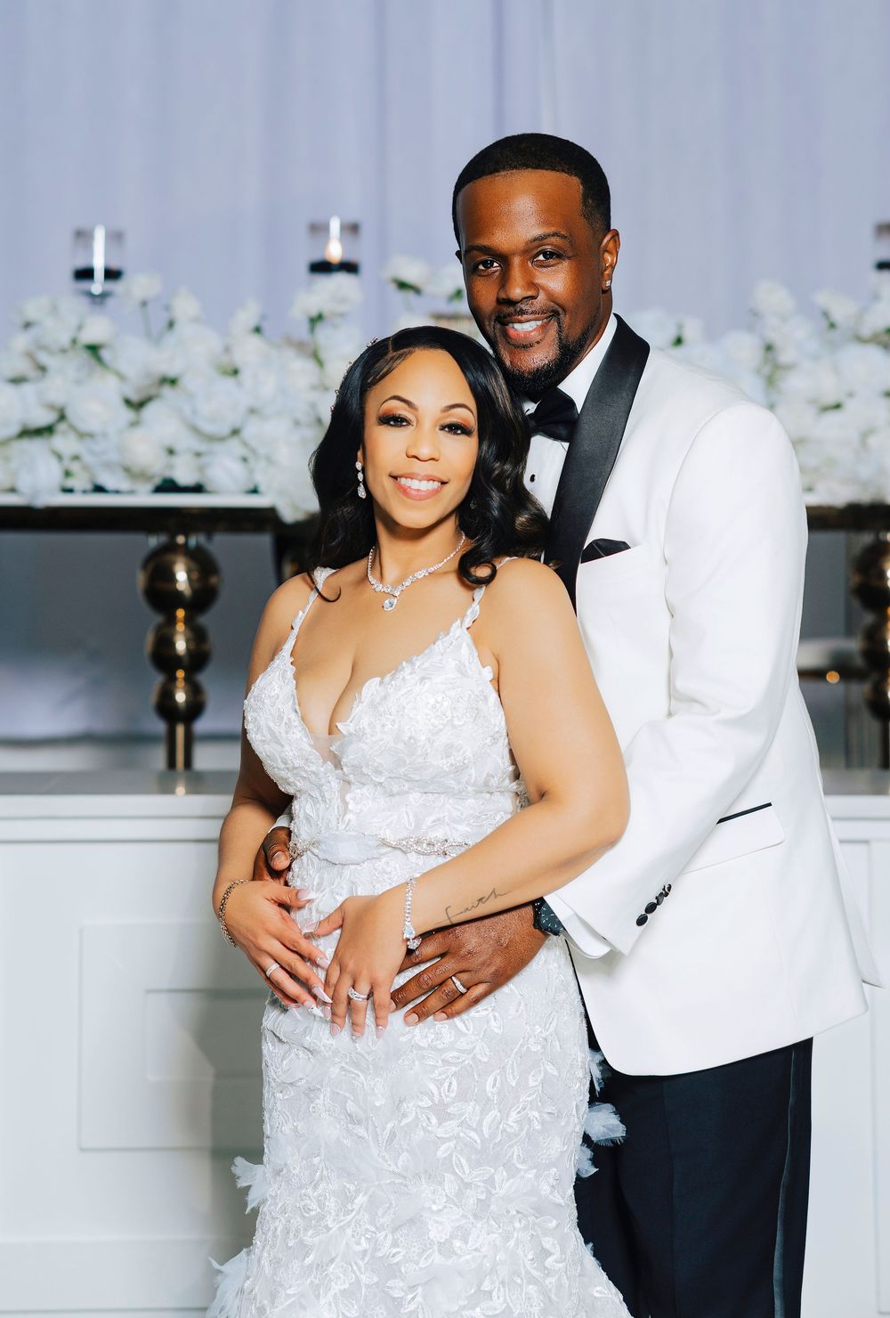 Romantic wedding photos showing a couple in white formal attire posing together against an elegant floral backdrop.