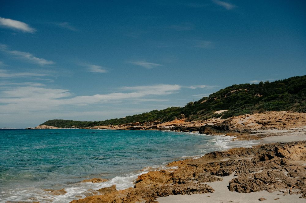 Scenic coastal landscape with turquoise waters and rocky shoreline under blue skies.