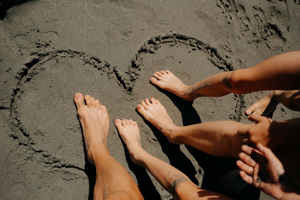 Bare feet relaxing on a sandy beach with ocean waves in the background.