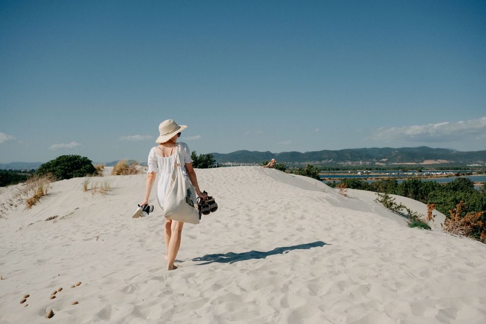 Sandy beach pathway leading to the ocean with mountains visible in the distance.