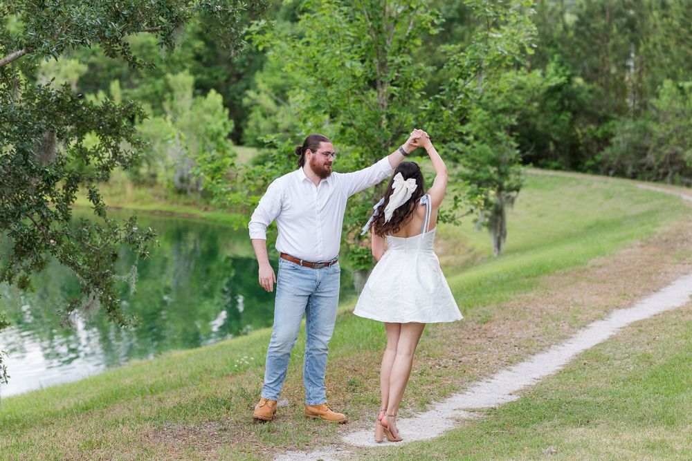 Couple enjoying a romantic stroll along a scenic path near a lake surrounded by lush greenery.