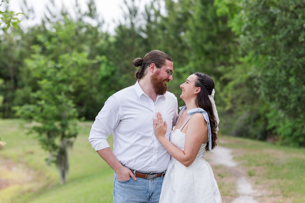 A couple shares a romantic moment together on a scenic dirt path surrounded by lush greenery.