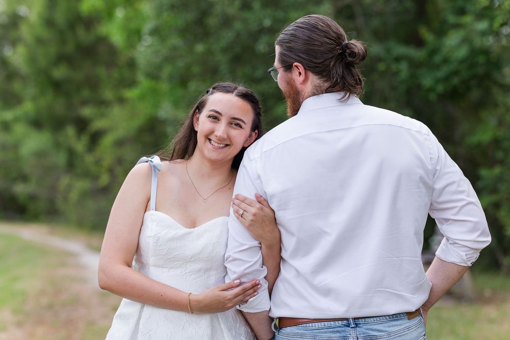 Couple walking hand in hand down a scenic outdoor path surrounded by lush greenery.