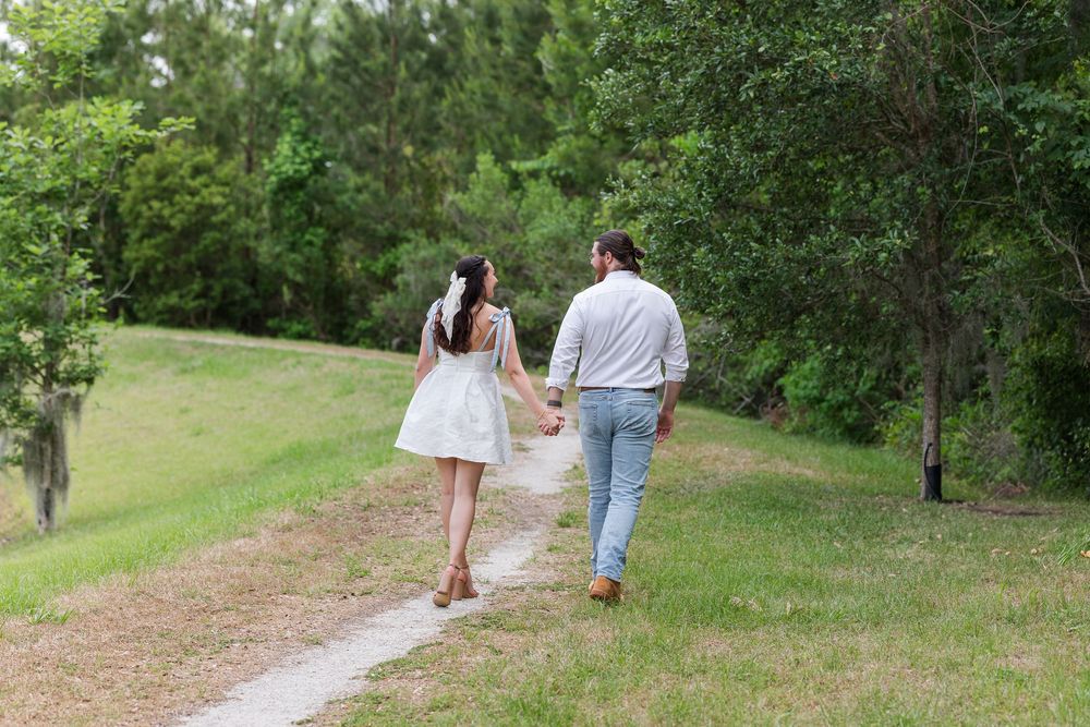 Romantic couple strolling together on a winding nature trail through green foliage.