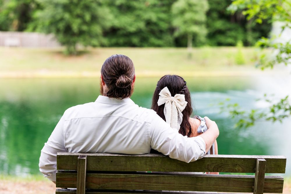 Couple sharing an intimate moment on a wooden bench overlooking a serene lake.