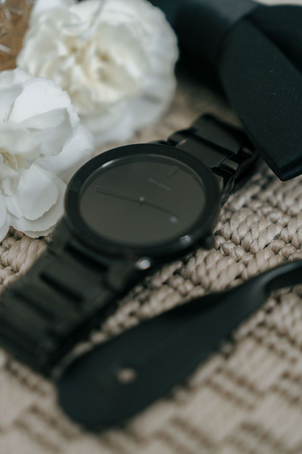 A close-up view of a black wristwatch next to white crumpled tissue paper on a textured surface.
