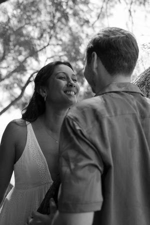 A romantic black and white portrait of a couple sharing an intimate moment outdoors with soft bokeh background.