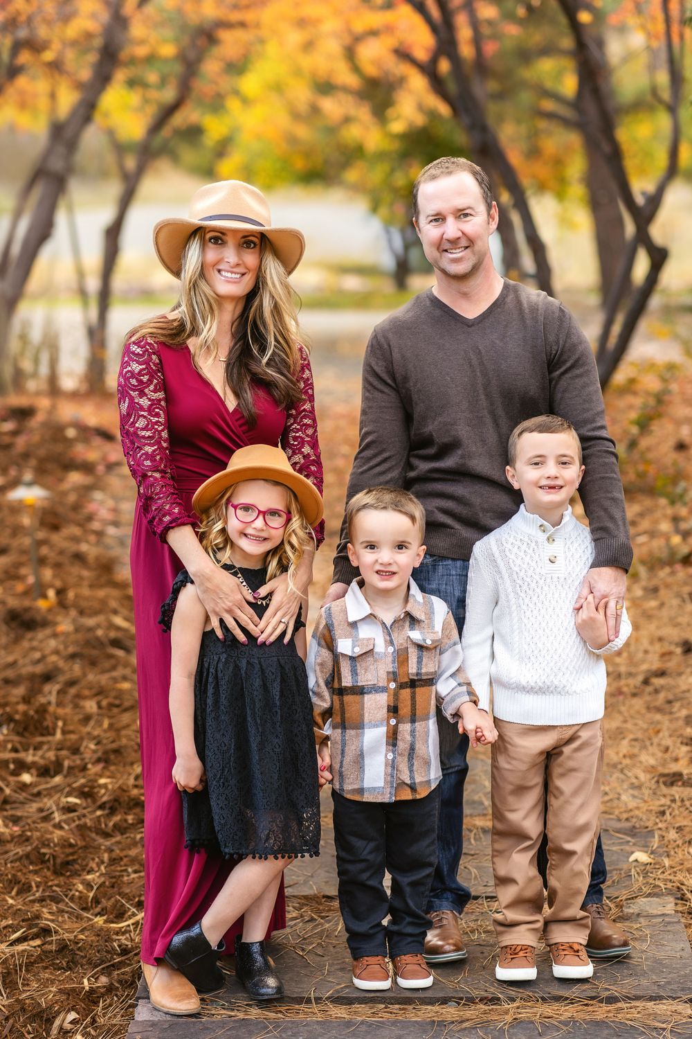 Family of five posing in colorful autumn park setting.