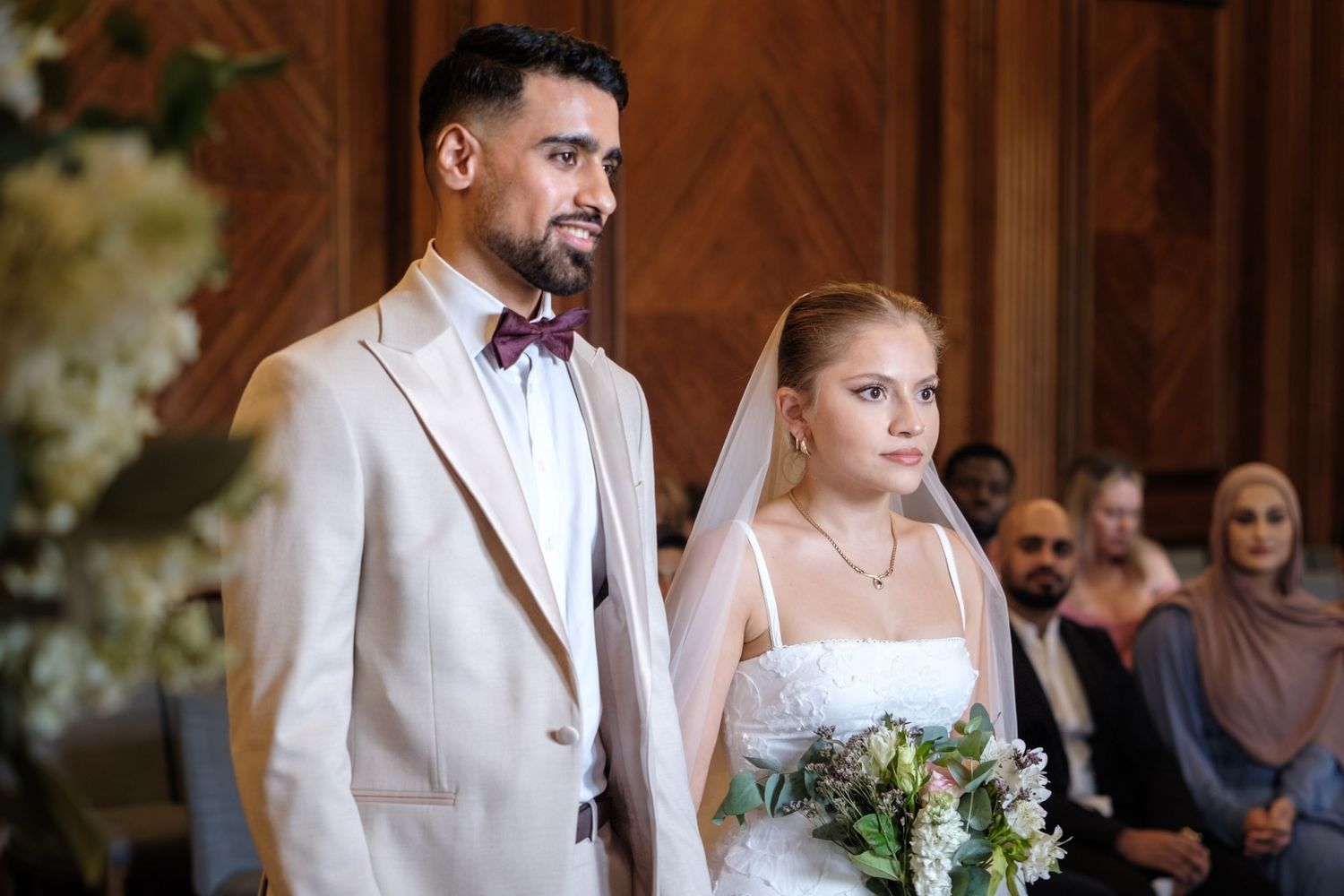 A large group of people, including a bride and groom, posing together outside a building.