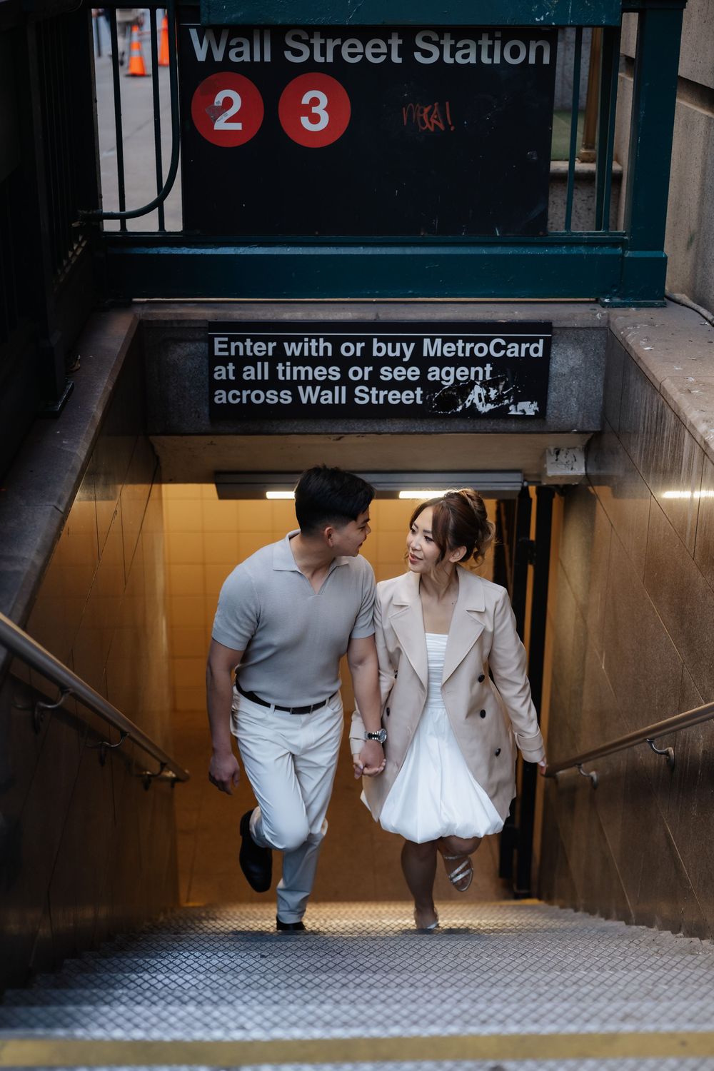 Couple holding hands emerging from Wall Street Station subway entrance in New York City.