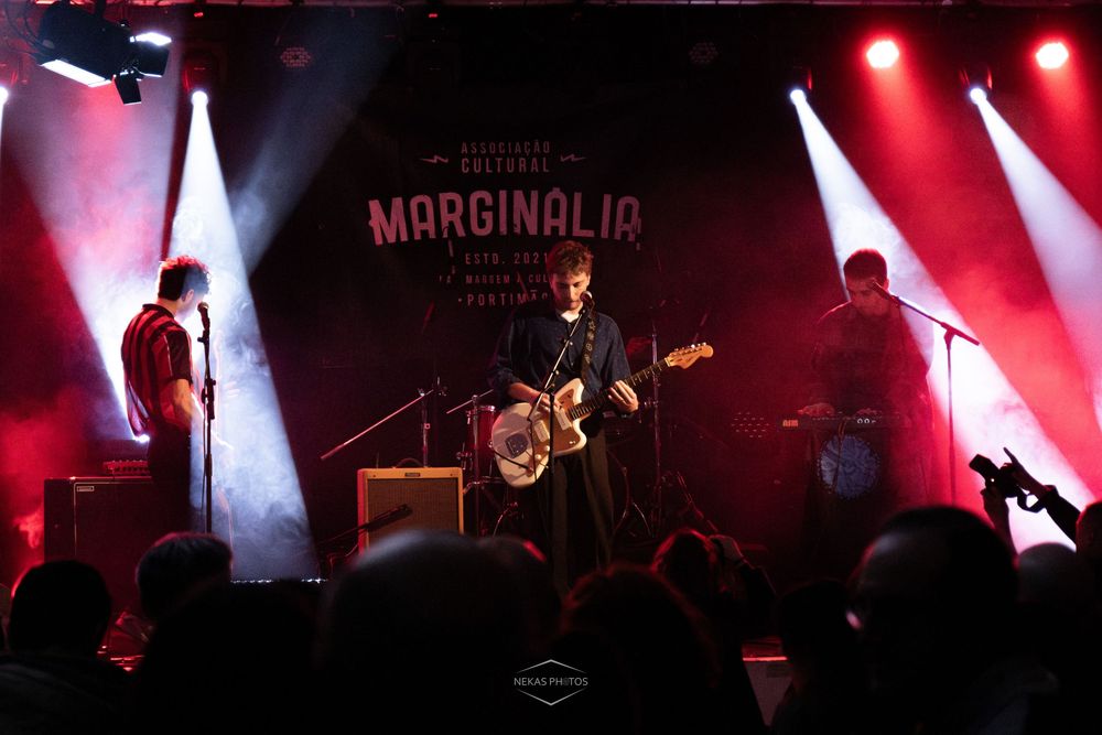 Band performing live on stage at Marginalia cultural festival under dramatic red and white stage lighting.