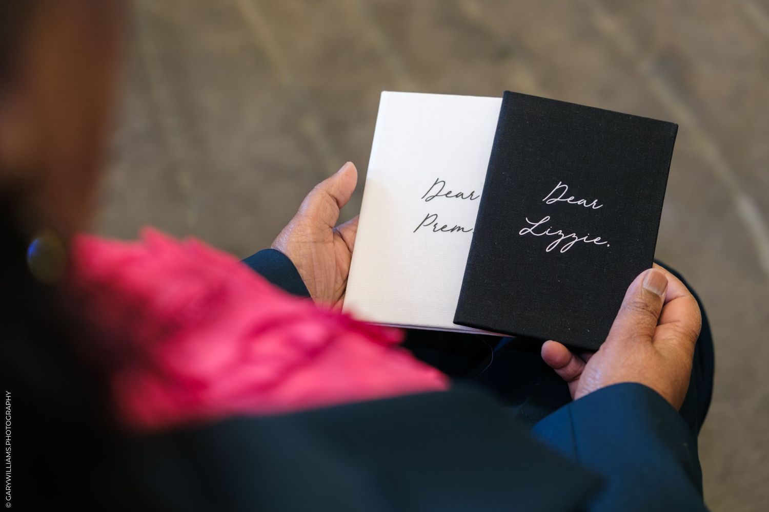 Person holding open a black and white card reading Dear Lizzie at a formal event.