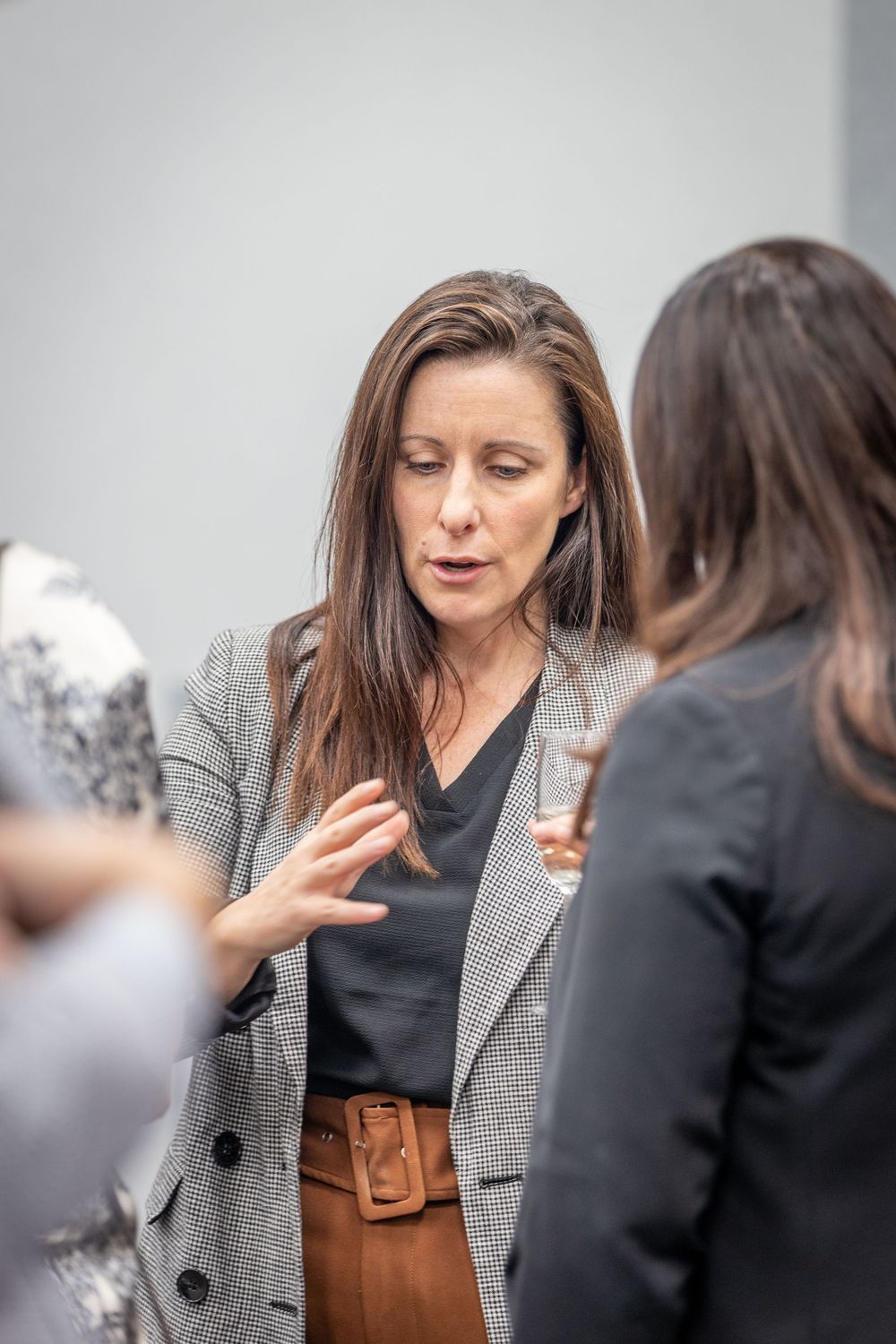 Professional woman in blazer gesturing while networking at a business event.