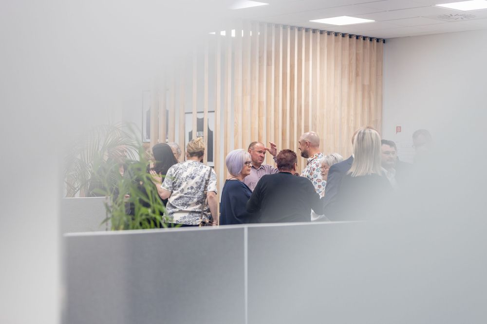 Group of office professionals having a meeting in a modern conference room with vertical blinds and plants.