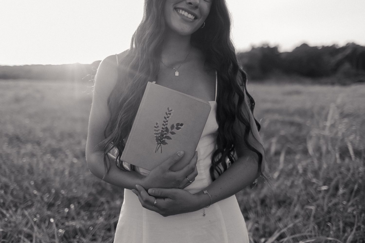 A black and white portrait of someone laughing joyfully outdoors.