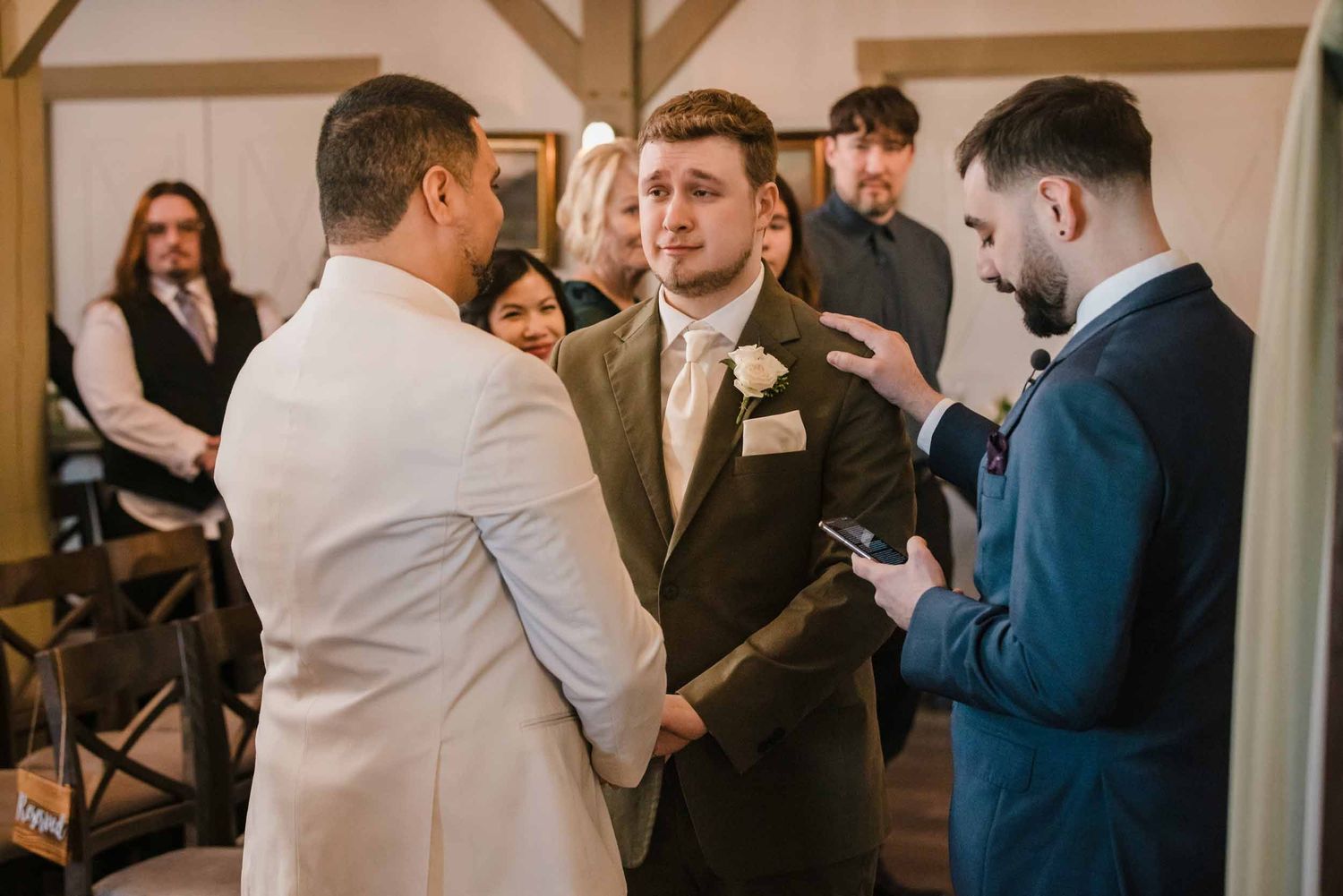 Couple holding hands during wedding vows and ring exchange at Briar Barn Inn indoor ceremony