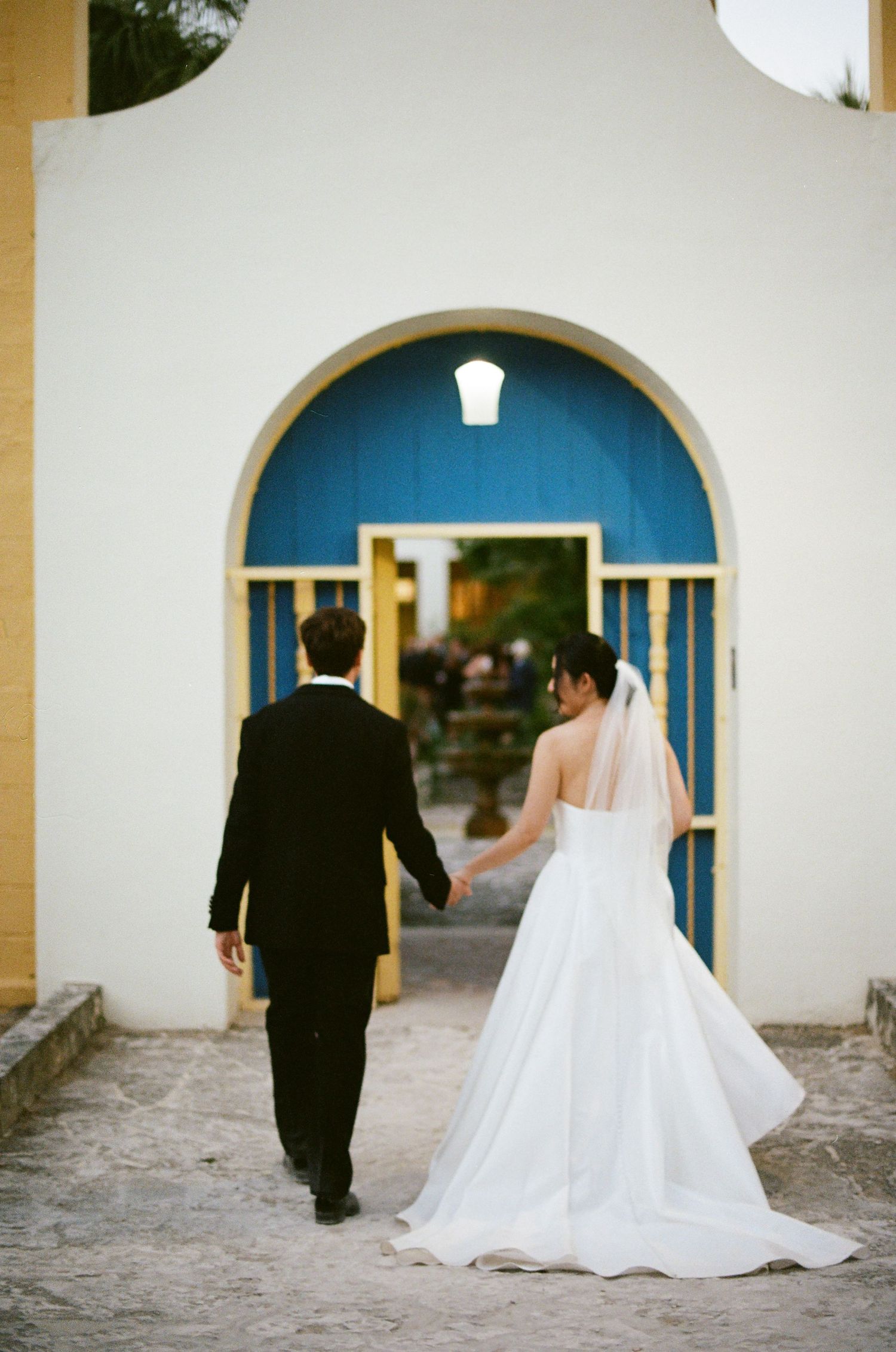 A couple in wedding attire dances together at sunset in front of a grand historic building.