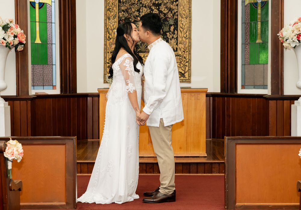 A couple shares a romantic kiss at the altar during their wedding ceremony in a beautiful church.