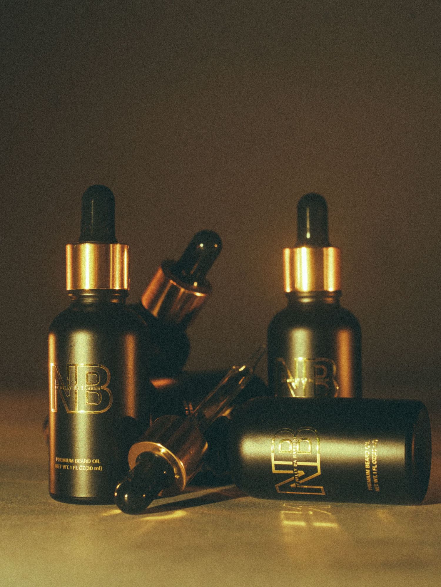 Luxury NB black dropper bottles with gold accents arranged on a warm surface, showcasing premium skincare serum packaging.