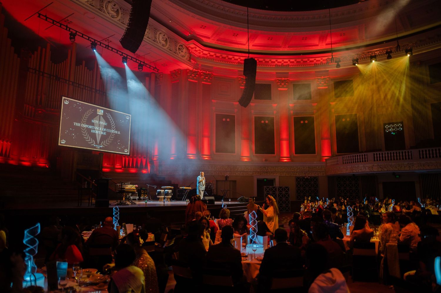 Colorful red and yellow lighting illuminates historic venue during nighttime event.
