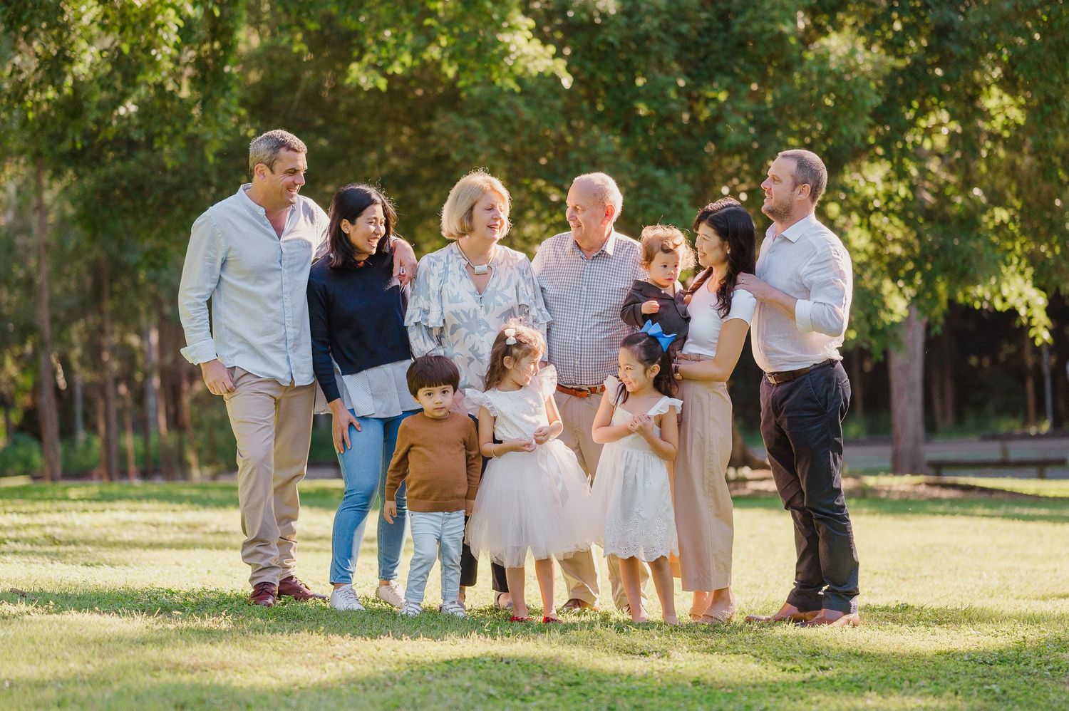 Extended family poses together for outdoor portrait in garden setting.