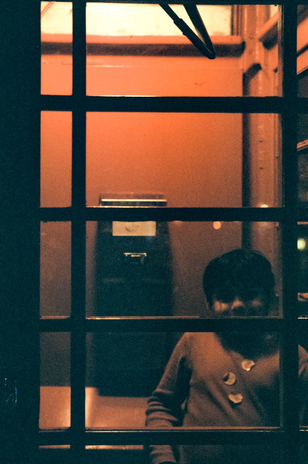 Warm-lit interior scene viewed through a geometric window frame at dusk.