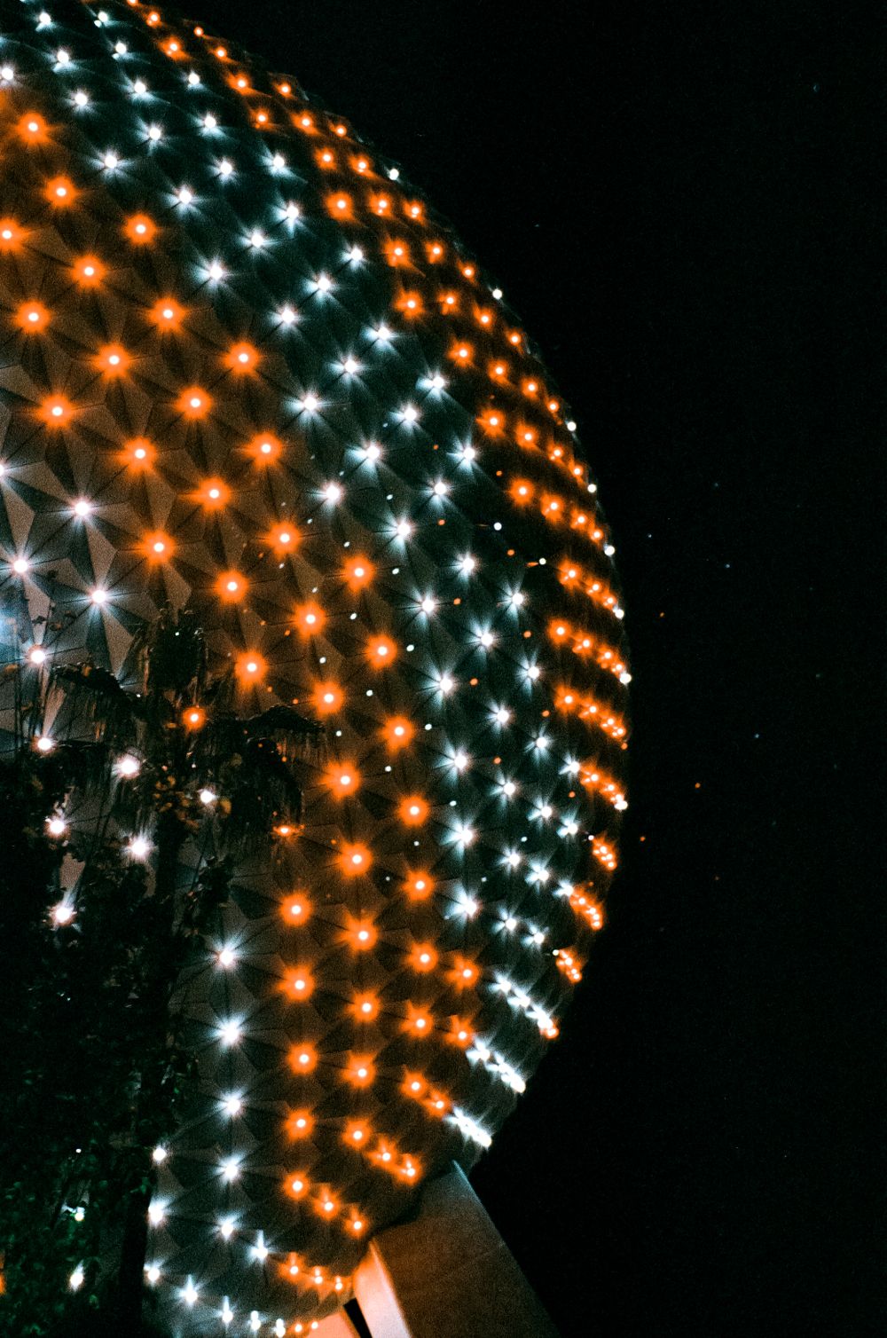 Pattern of orange and white lights creating a curved geometric display against the night sky.