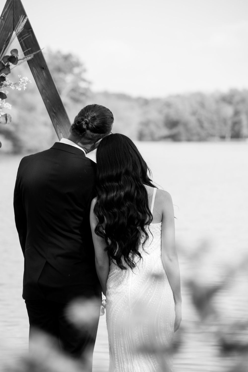 A romantic black and white wedding photo showing a couple gazing at a scenic lakeside view.