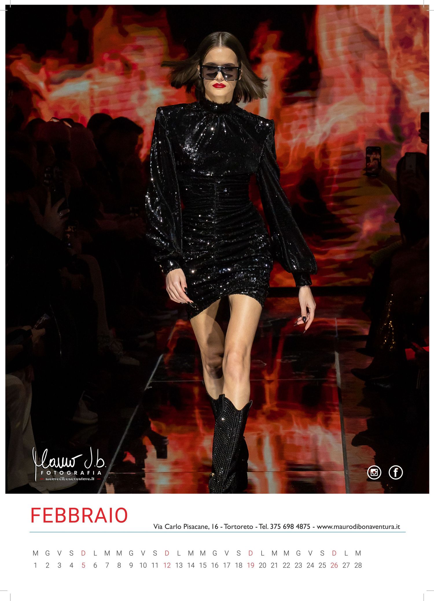 Model walks runway in sparkly black mini dress and boots against dramatic red backdrop for February calendar.