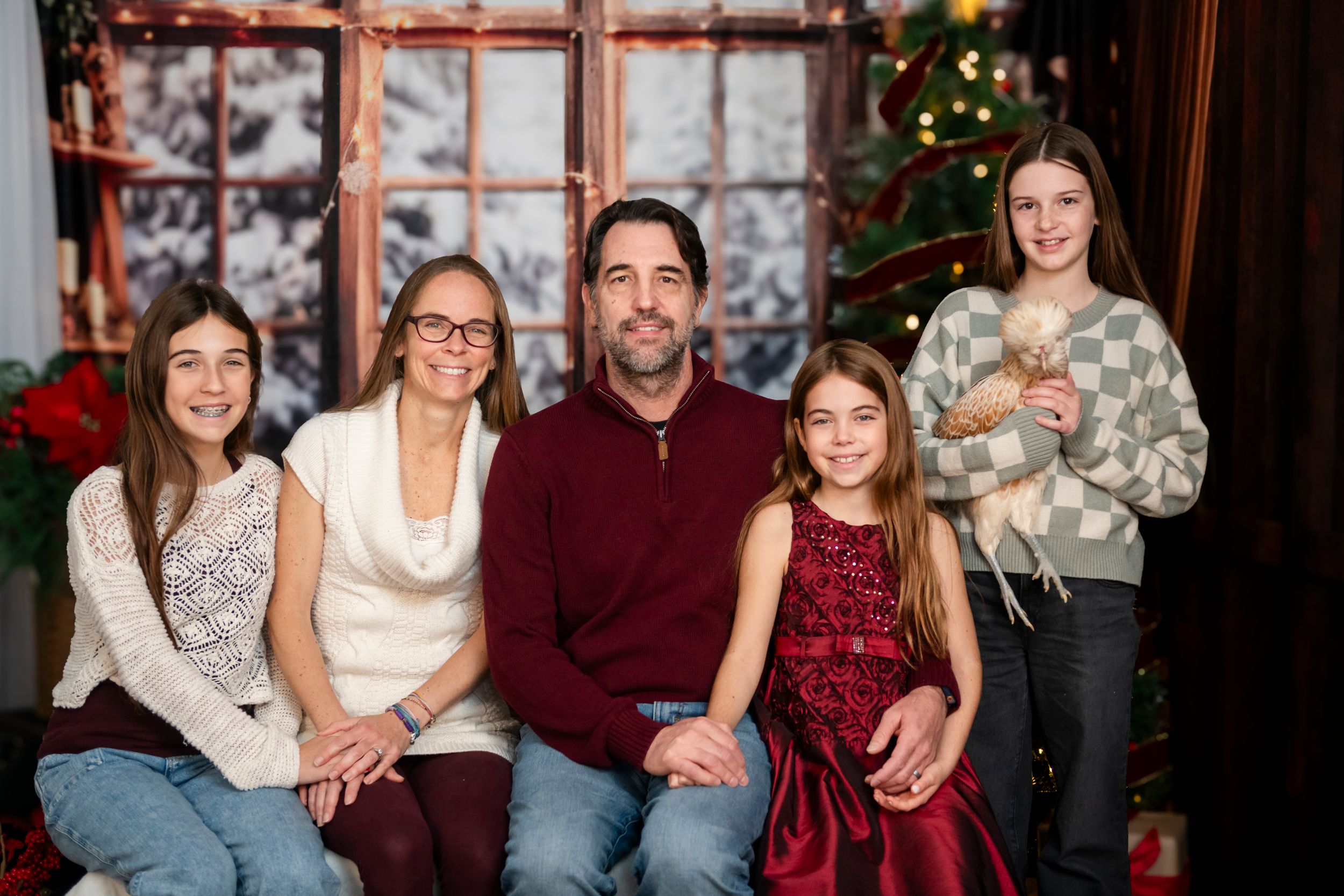 A cozy indoor family portrait during the holiday season with festive decor and winter outfits.
