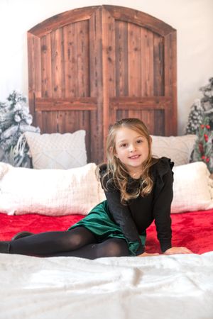 Holiday portrait with rustic wooden headboard, red blanket, and Christmas decor in background.