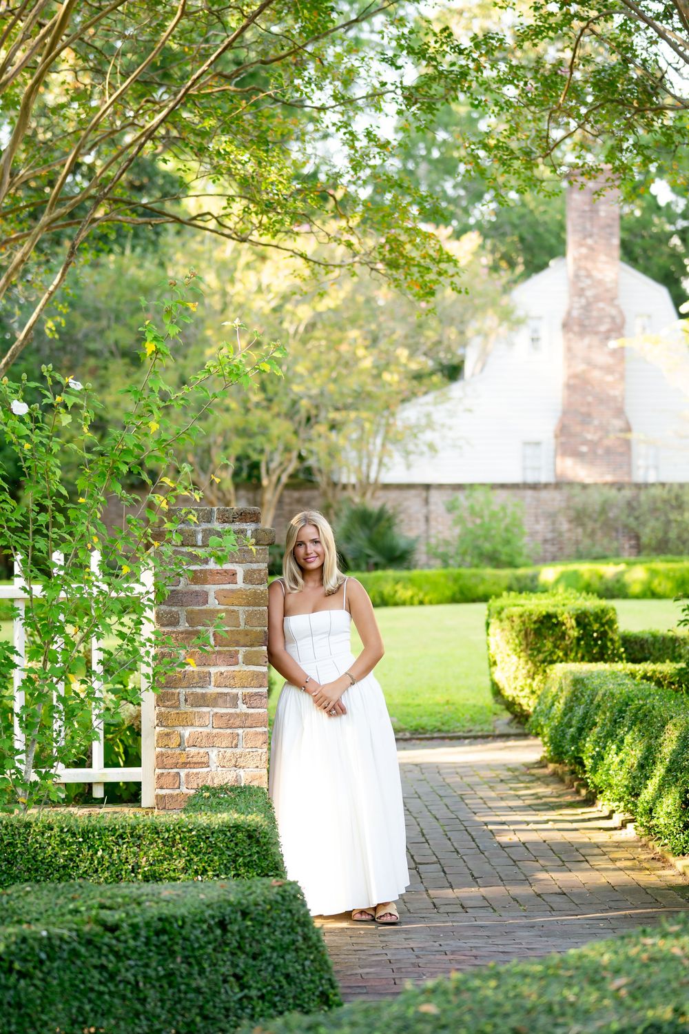 A series of outdoor portraits taken in a lush garden setting with brick pathways and green hedges on a sunny day.