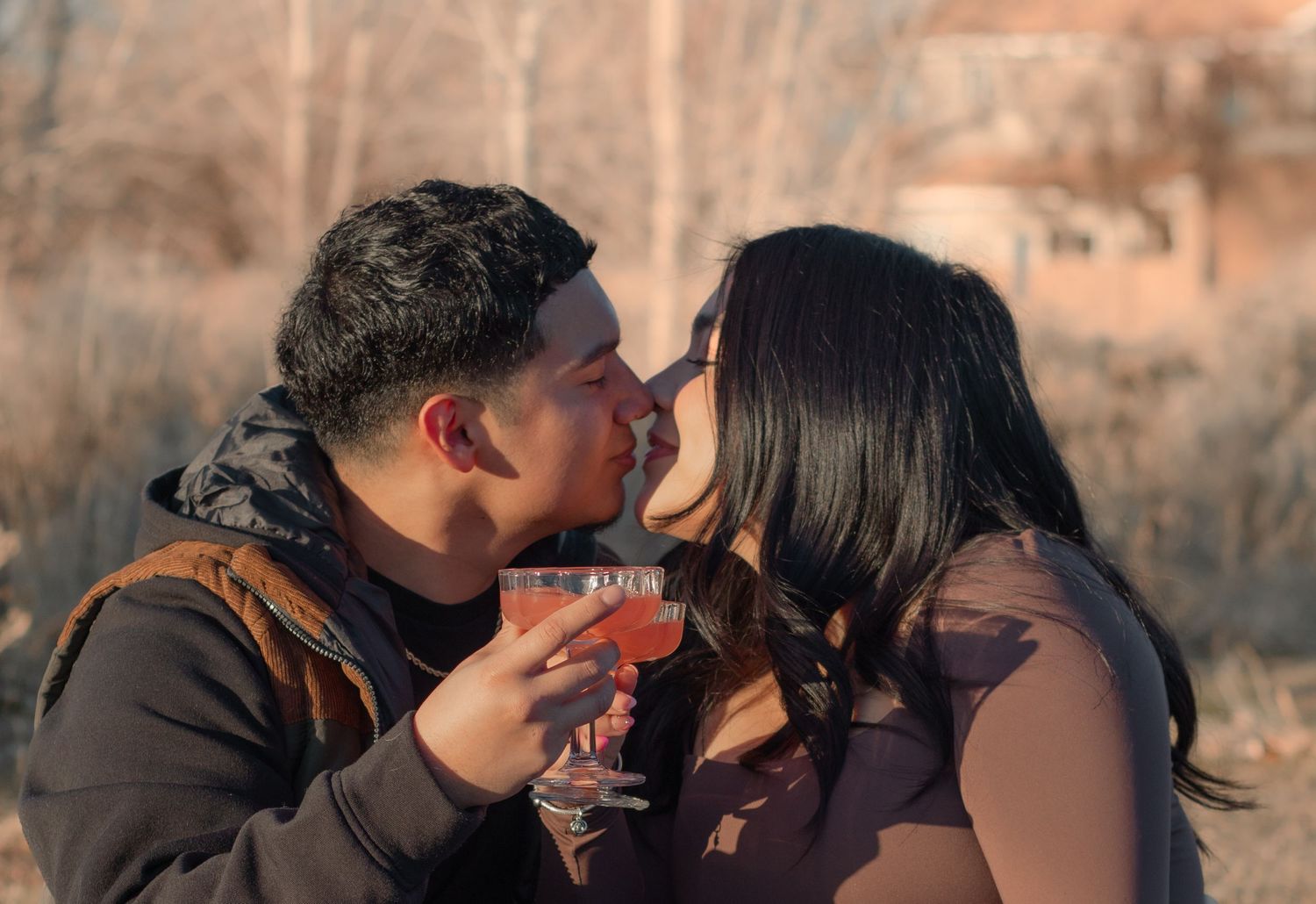 Couple sharing a kiss while holding drinks during golden-hour couples session in Eastern Washington